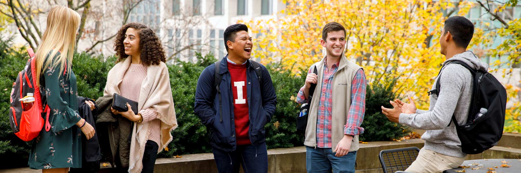 Students talk outside on campus in autumn.