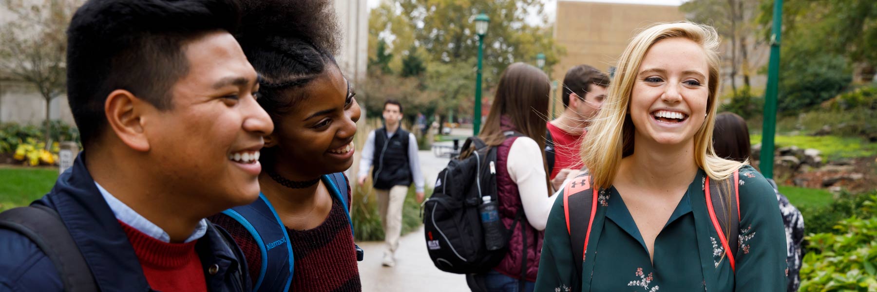 three people smiling outside a building on campus